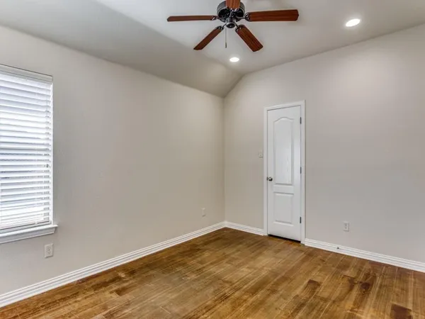 a view of empty room with wooden floor and fan