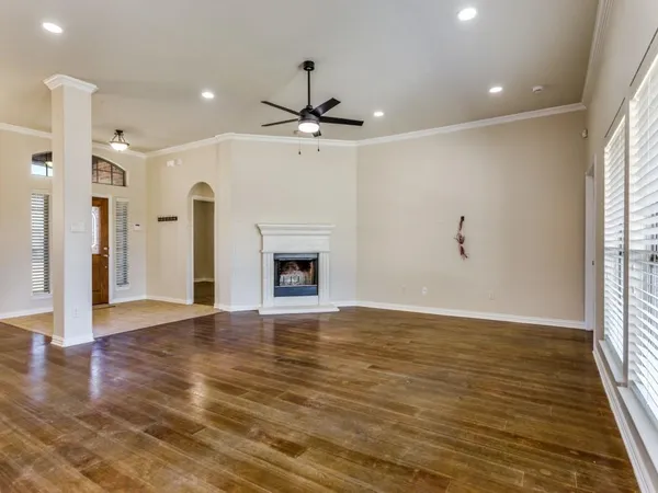 an empty room with wooden floor fireplace and windows