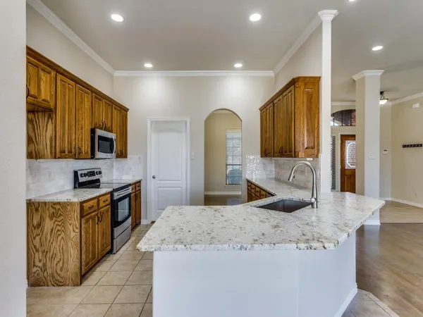 a large kitchen with stainless steel appliances wooden floor and a refrigerator