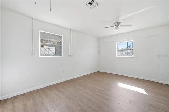 a view of an empty room with a window and wooden floor