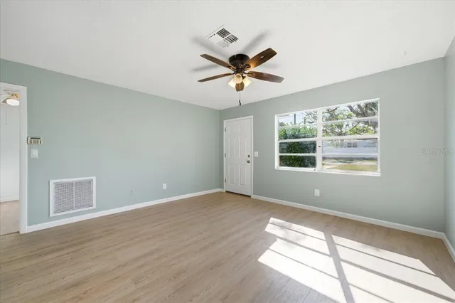 a view of empty room with wooden floor and fan