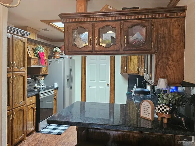 a kitchen with kitchen island granite countertop a stove top oven microwave and cabinets