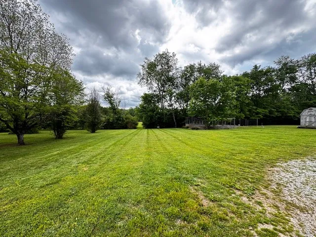 a front view of house with yard and trees in the background