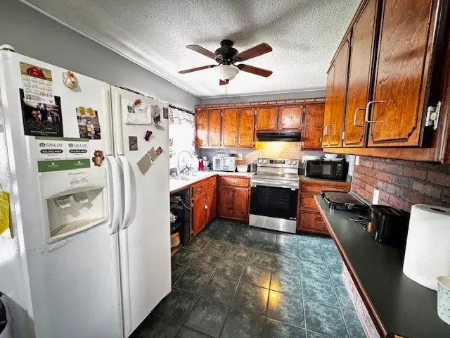 a kitchen with stainless steel appliances a sink a stove a refrigerator cabinets and a window