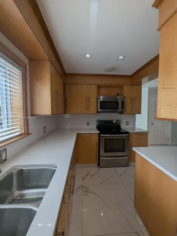a kitchen with granite countertop a sink and stainless steel appliances
