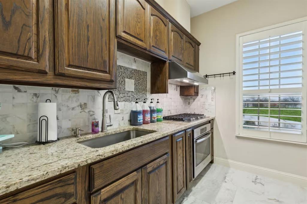 1405 Gateway Boulevard Forney, TX 75126 - Photo 11 of 32 a kitchen with granite countertop a sink a stove and cabinets