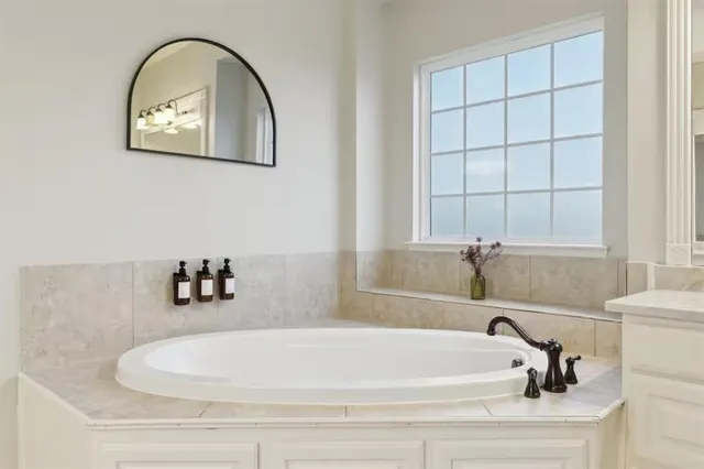 a large white bathroom with a tub sink and mirror