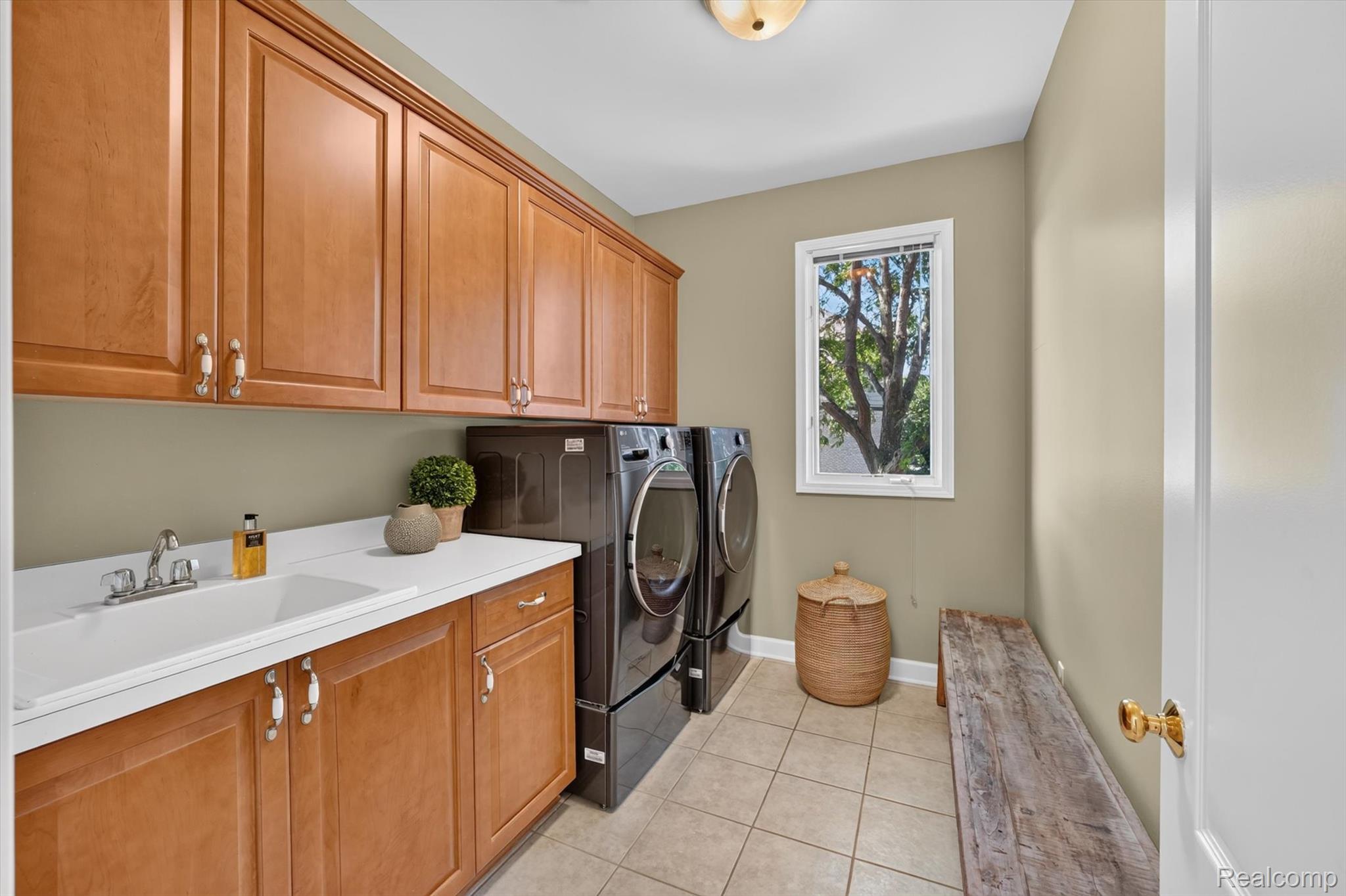 3804 Elk Drive Rochester, MI 48306 - Photo 20 of 75 Dedicated laundry area featuring extensive wood cabinetry, a built-in utility sink, neutral tile flooring, and ample counter space