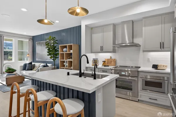 a kitchen with stainless steel appliances granite countertop a stove a sink a refrigerator and white cabinets with wooden floor