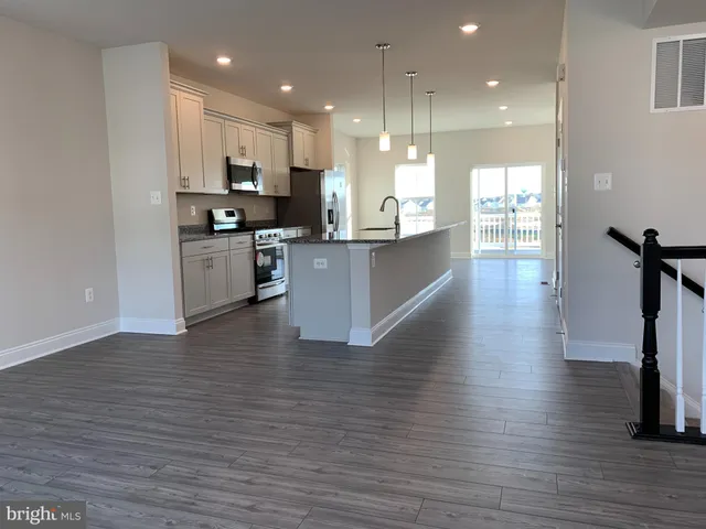 a kitchen with stainless steel appliances kitchen island granite countertop a stove top oven a sink and a refrigerator