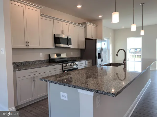 a kitchen with granite countertop a sink a counter top space cabinets and stainless steel appliances