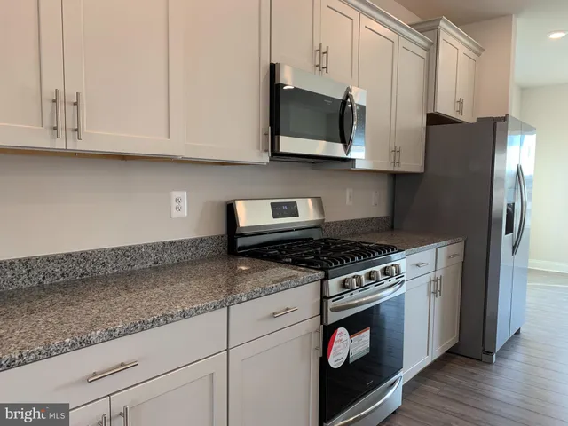 a kitchen with stainless steel appliances granite countertop white cabinets and a stove a oven with wooden floor