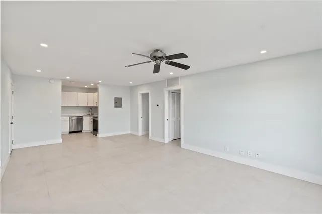 an empty room with chandelier fan and windows