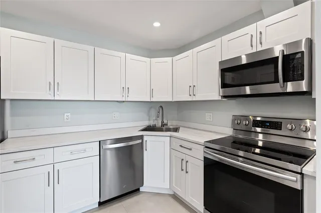 a kitchen with stainless steel appliances granite countertop grey cabinets a stove a sink and dishwasher
