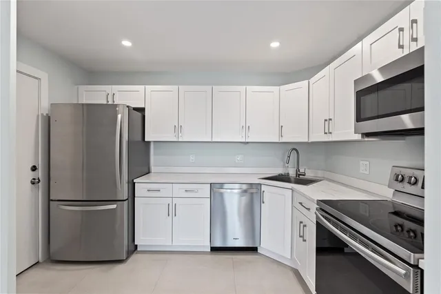 a kitchen with stainless steel appliances granite countertop a refrigerator a stove a sink and white cabinets