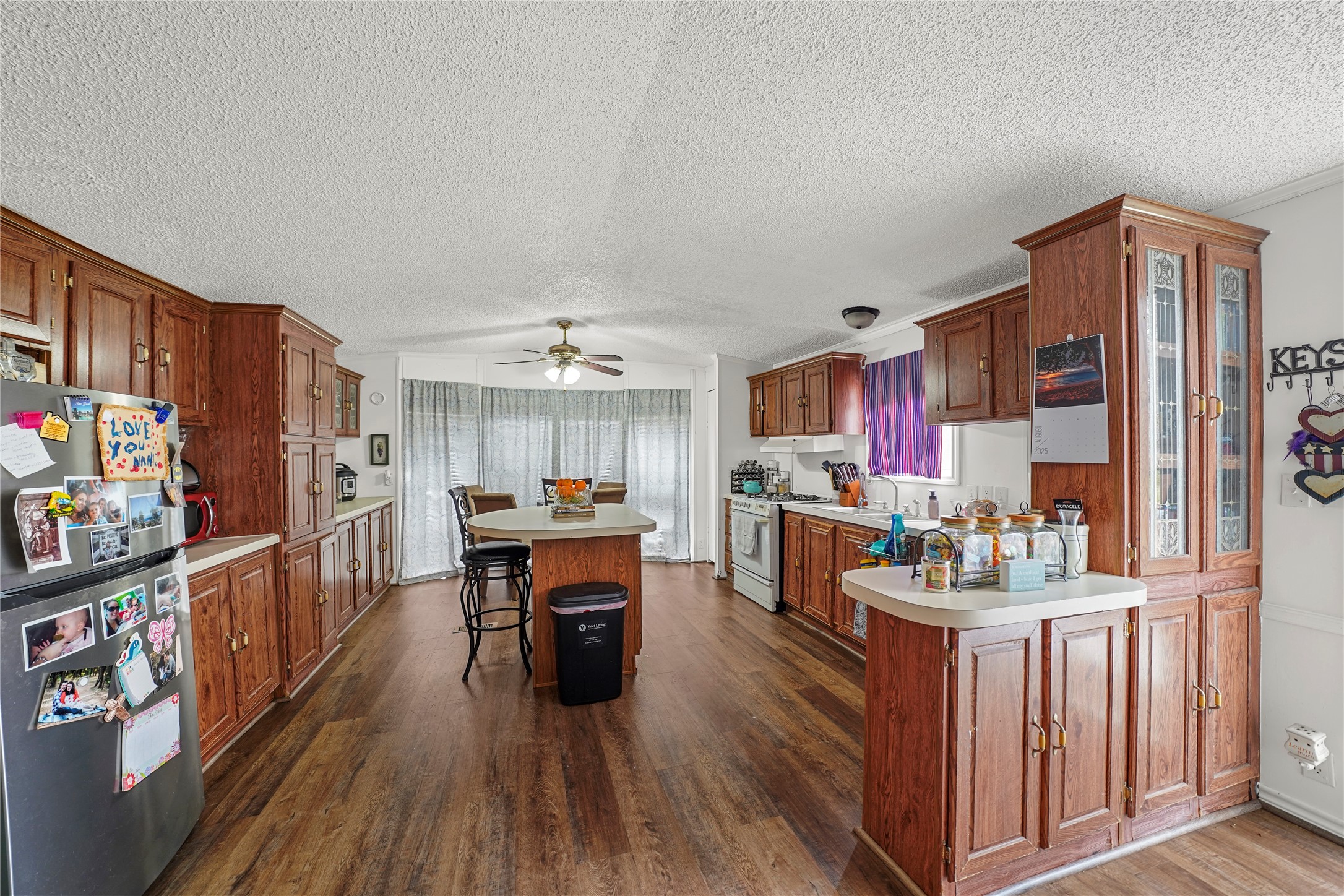 19645 Nordt Road Damon, TX 77430 - Photo 29 of 50 a kitchen with stainless steel appliances kitchen island granite countertop a refrigerator a stove top oven a dining table and chairs with wooden floor