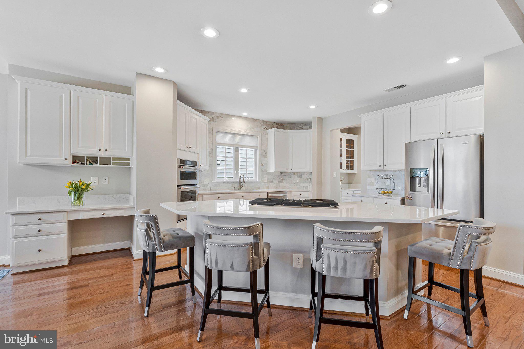 9183 Topaz Street Fairfax, VA 22031 - Photo 16 of 67 a kitchen with stainless steel appliances kitchen island granite countertop a table chairs stove and white cabinets