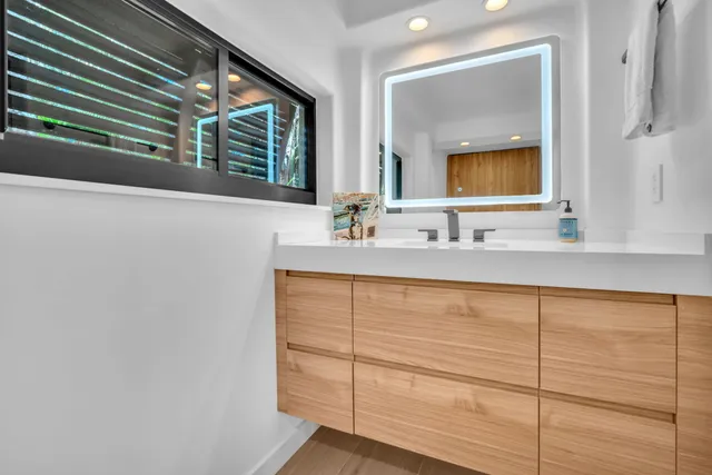 a bedroom with a bed a chair and potted plant on the dresser