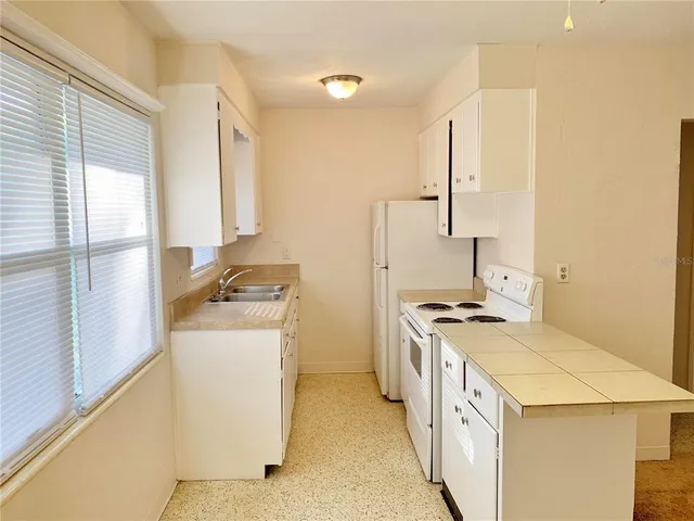 a kitchen with a stove a sink a refrigerator and a window