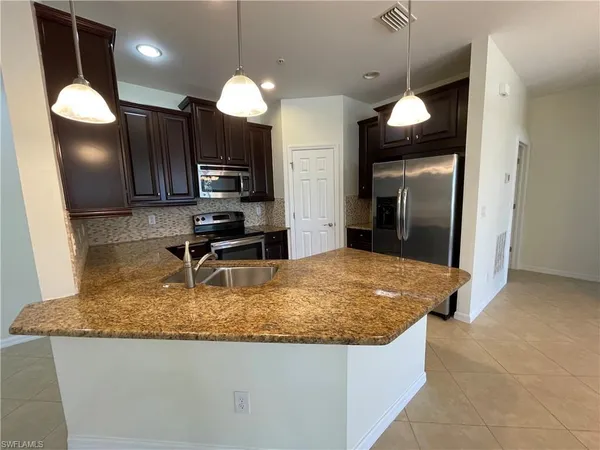 a kitchen with granite countertop a sink a counter and refrigerator