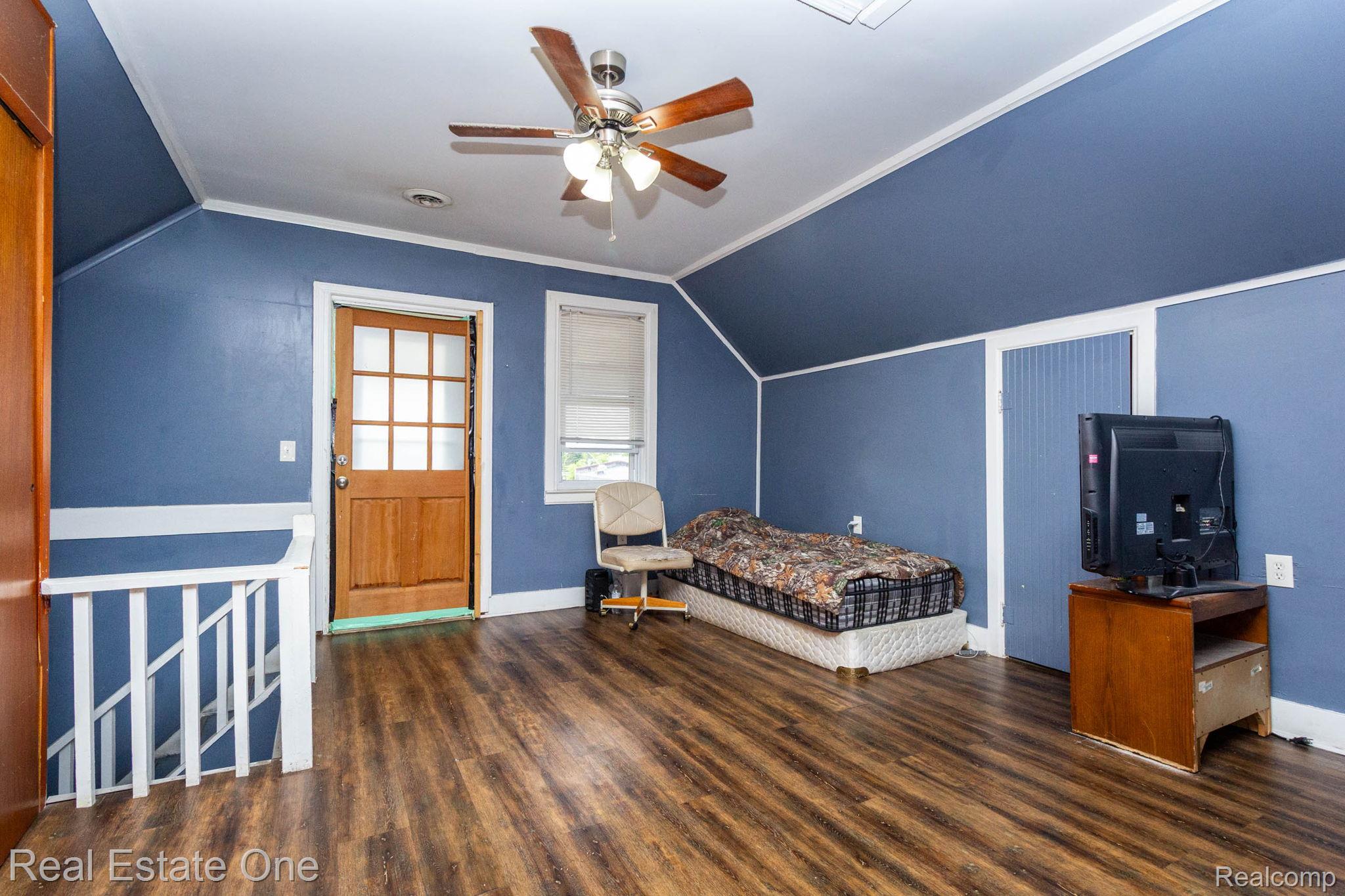 5485 Springwells Street Detroit, MI 48210 - Photo 24 of 47 Room featuring wood-finish flooring, blue walls with white trim, and a ceiling fan with light fixture