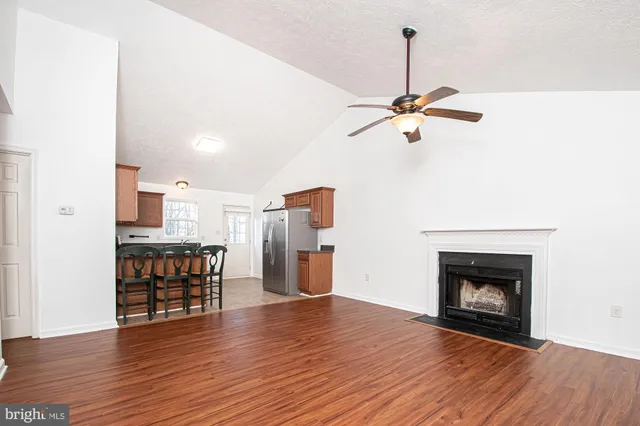 a view of a livingroom with a fireplace a ceiling fan and wooden floor