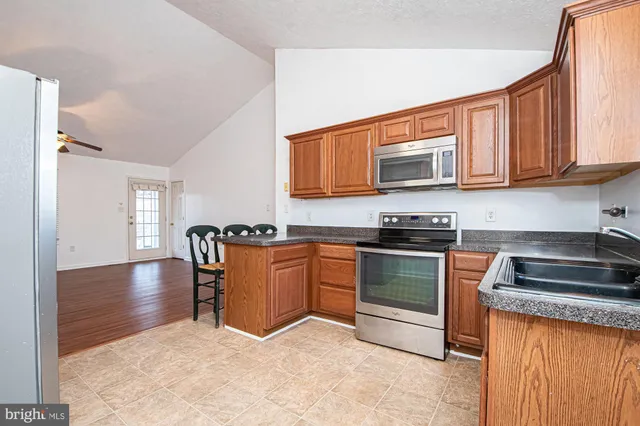 a kitchen with granite countertop a stove top oven a sink dishwasher and cabinets with wooden floor