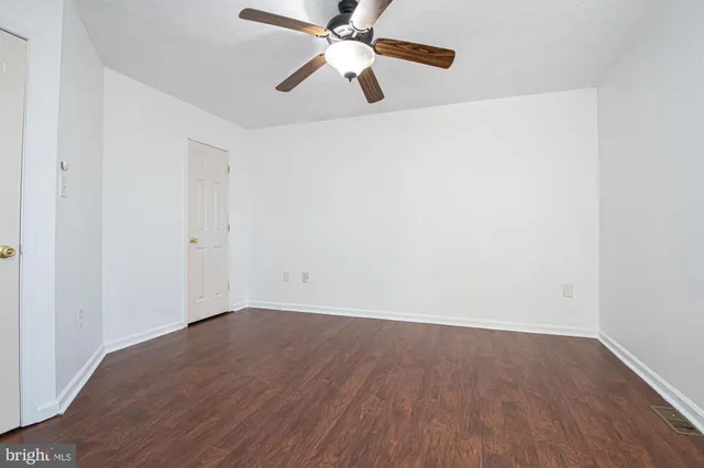 an empty room with wooden floor ceiling fan and a ceiling fan