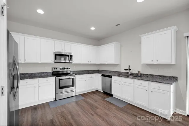 a kitchen with granite countertop white cabinets and white appliances