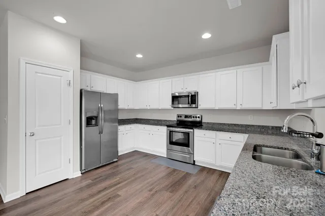 a kitchen with stainless steel appliances granite countertop a refrigerator sink and stove