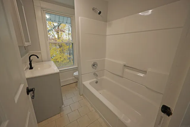 a bathroom with a tub a sink and a window