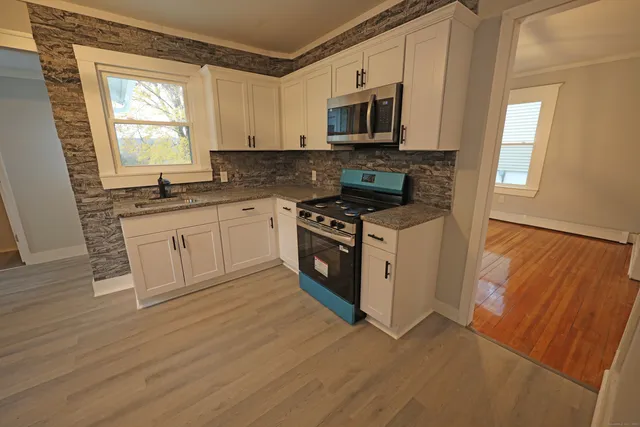 a kitchen with stainless steel appliances granite countertop a stove a sink and a microwave