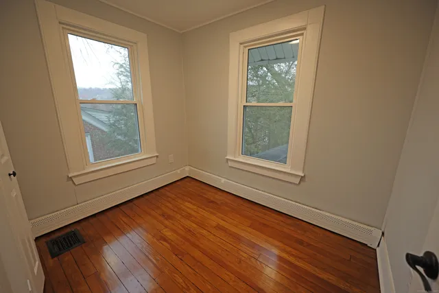 a view of an empty room with wooden floor and a window