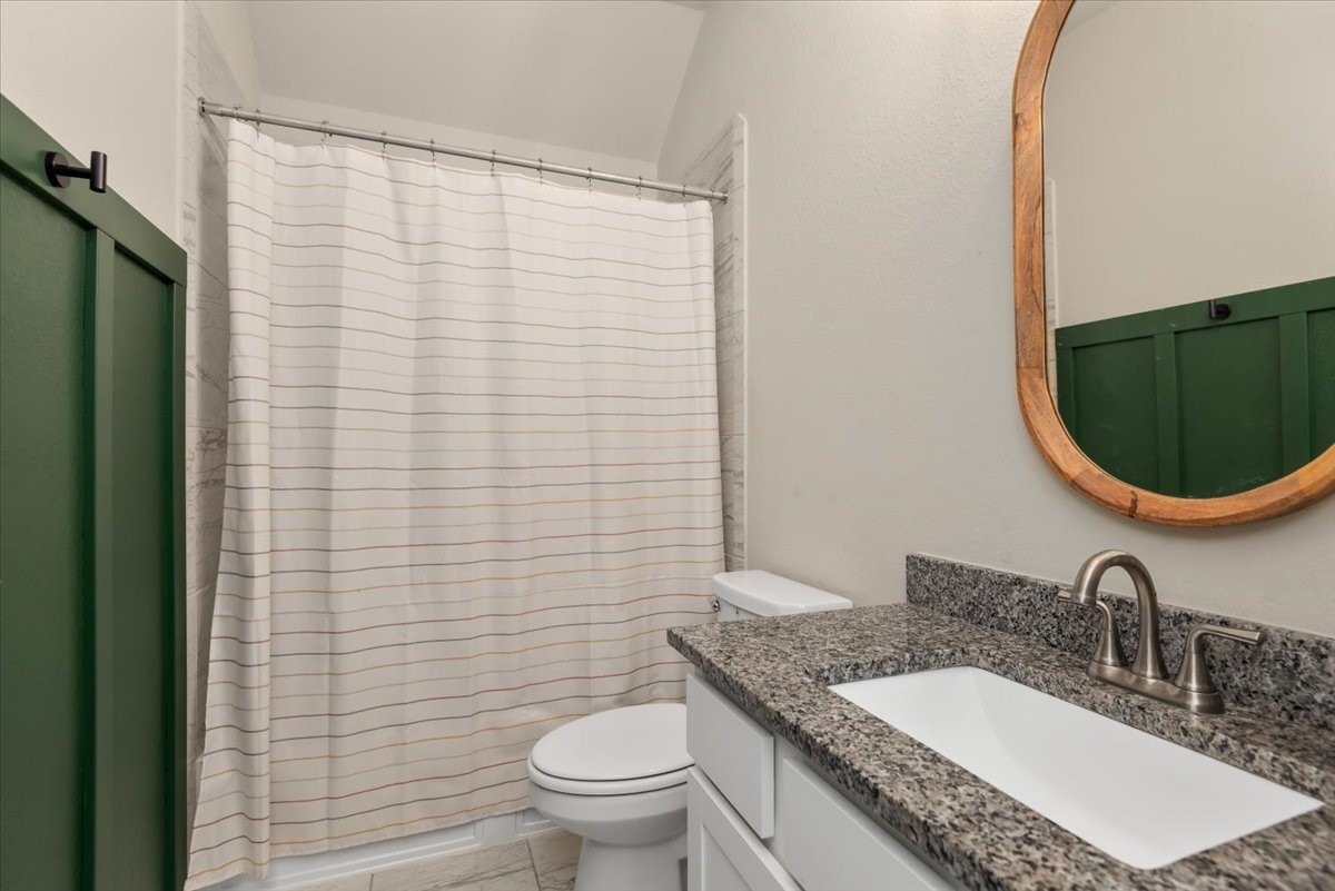 17814 Tree Of Heaven Conroe, TX 77385 - Photo 21 of 48 Full bathroom featuring granite countertops, updated fixtures, and stylish board and batten wall trim that adds character and design appeal, along with a clean tub/shower combination.