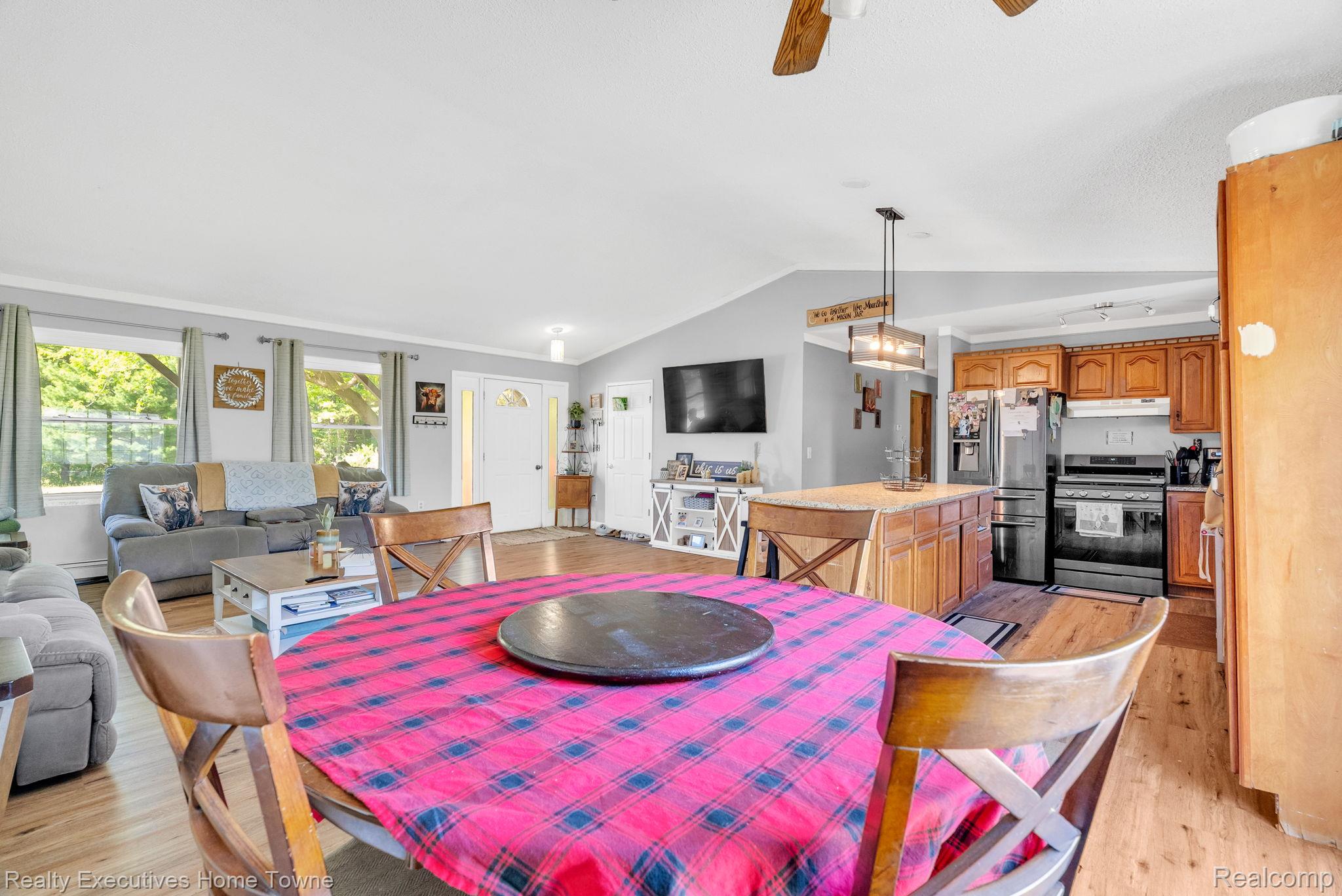 6560 Roach Road Lexington, MI 48450 - Photo 11 of 36 Open-concept living space featuring wood-finish flooring, a kitchen island, stainless steel appliances, and a vaulted ceiling