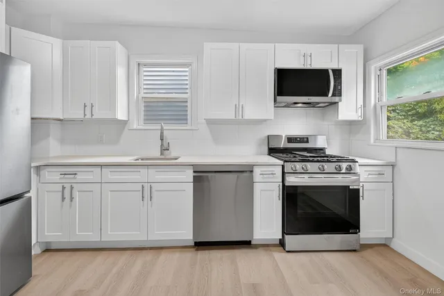 a kitchen with stainless steel appliances a stove a sink and a microwave