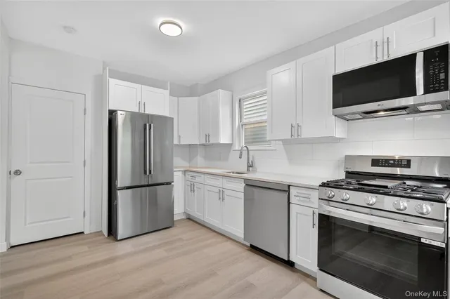 a kitchen with cabinets stainless steel appliances and wooden floor