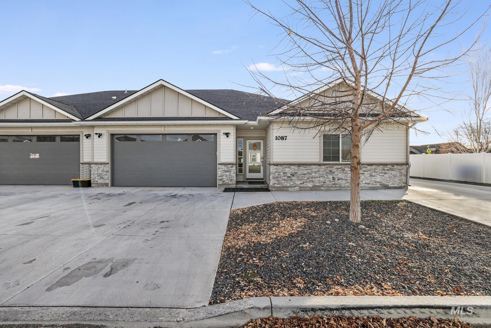 View of front facade featuring concrete driveway, stone siding, board and batten siding, a shingled roof, and an attached garage