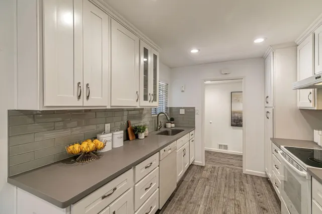 a kitchen with stainless steel appliances a sink dishwasher stove refrigerator and cabinets