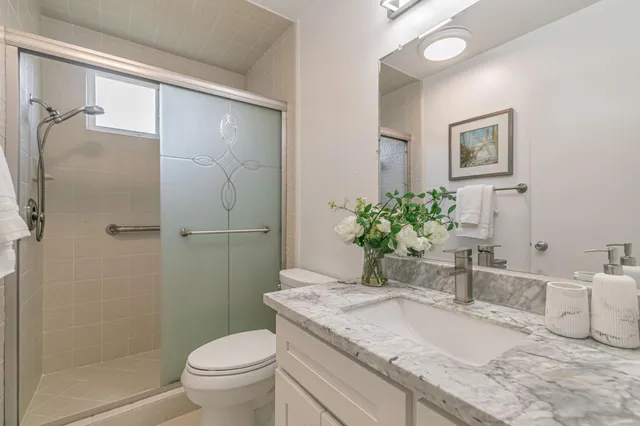 a bathroom with a granite countertop sink a toilet and shower
