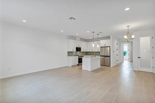 a kitchen with stainless steel appliances a refrigerator a stove a sink and white cabinets