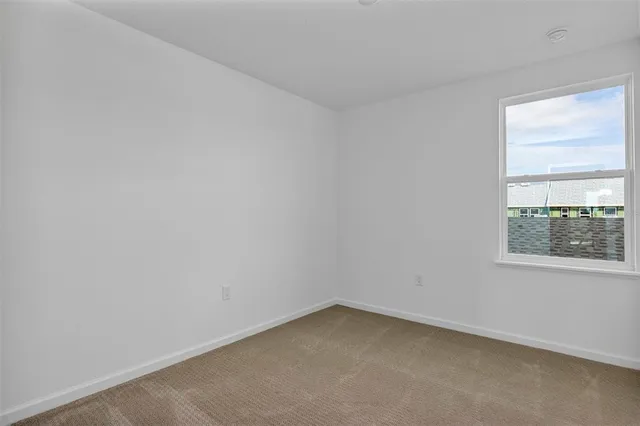 a view of an empty room with window and chandelier