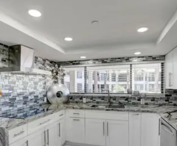 a kitchen with granite countertop white cabinets and stainless steel appliances