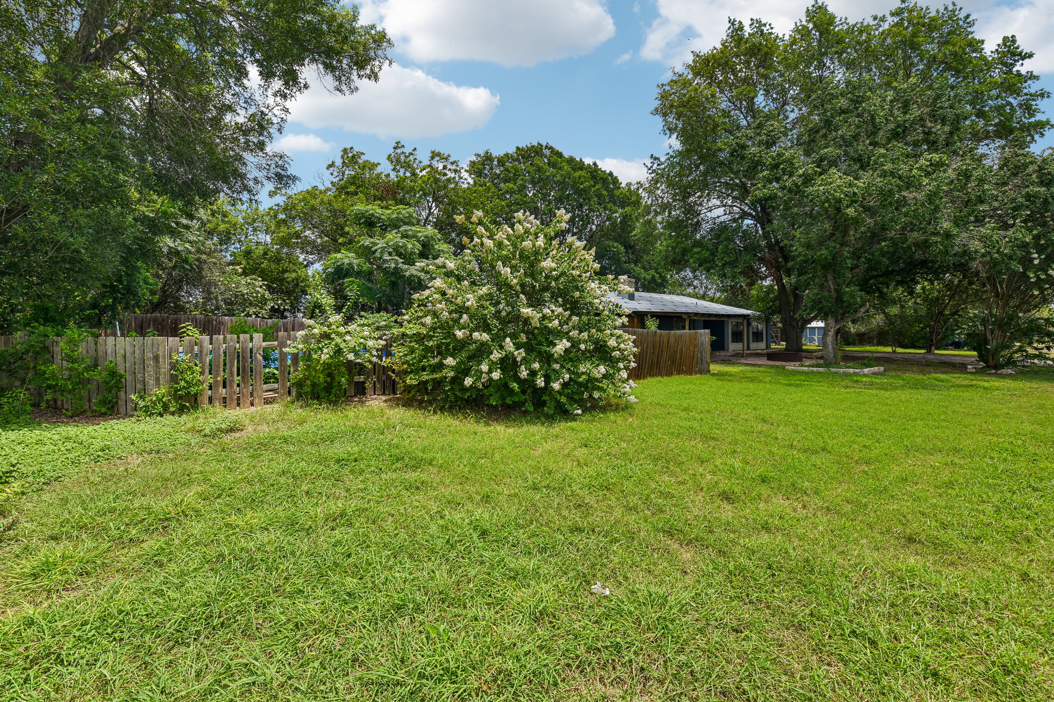 1111 Silent Valley Road Lockhart, TX 78644 - Photo 14 of 14 A verdant lawn provides a spacious backdrop for outdoor enjoyment, bordered by mature trees and a charming wooden fence.