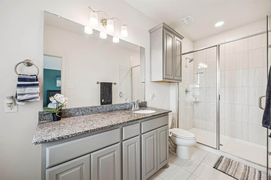 1010 Switchgrass Lane Allen, TX 75013 - Photo 17 of 25 a bathroom with a granite countertop sink a toilet a mirror and shower