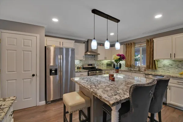 a kitchen with granite countertop kitchen island stainless steel appliances a sink cabinets and wooden floor