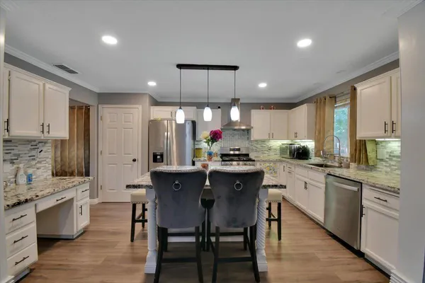 a kitchen with stainless steel appliances kitchen island granite countertop a table chairs sink and cabinets