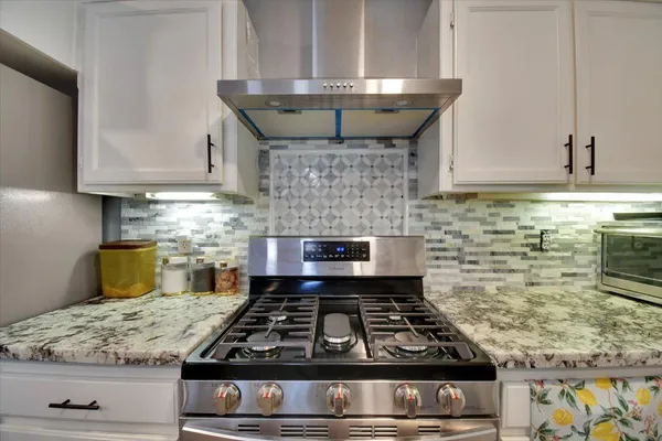 a kitchen with granite countertop a stove sink and cabinets