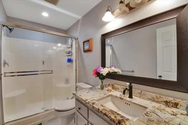 a bathroom with a granite countertop sink toilet and shower