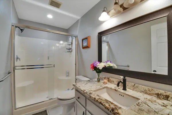 a bathroom with a granite countertop sink toilet and shower